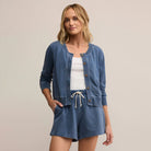 Woman wearing a blue cardigan and shorts set on a beige background