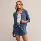 Woman wearing a blue cardigan and shorts set on a beige background
