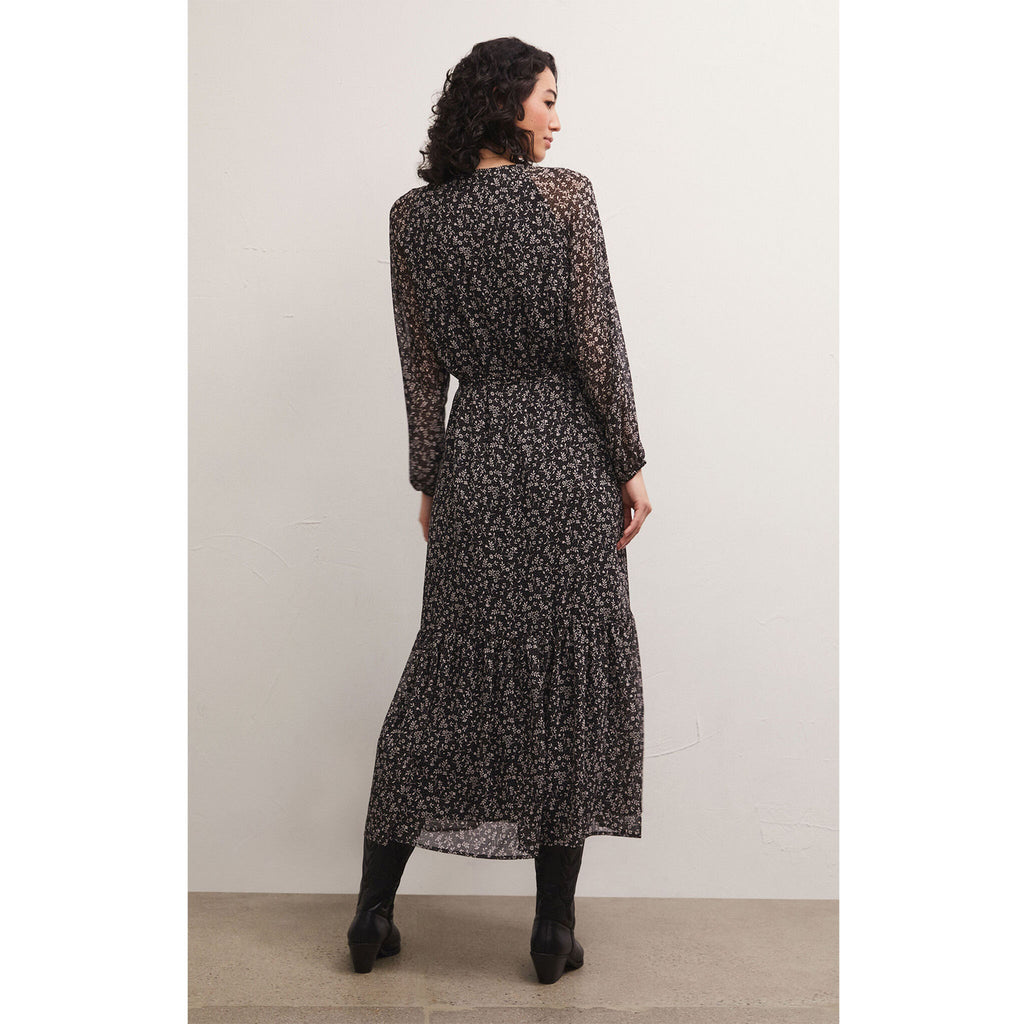 Brunette model wearing Z Supply Della Floral Midi Dress in Black with black boots in front of a white background