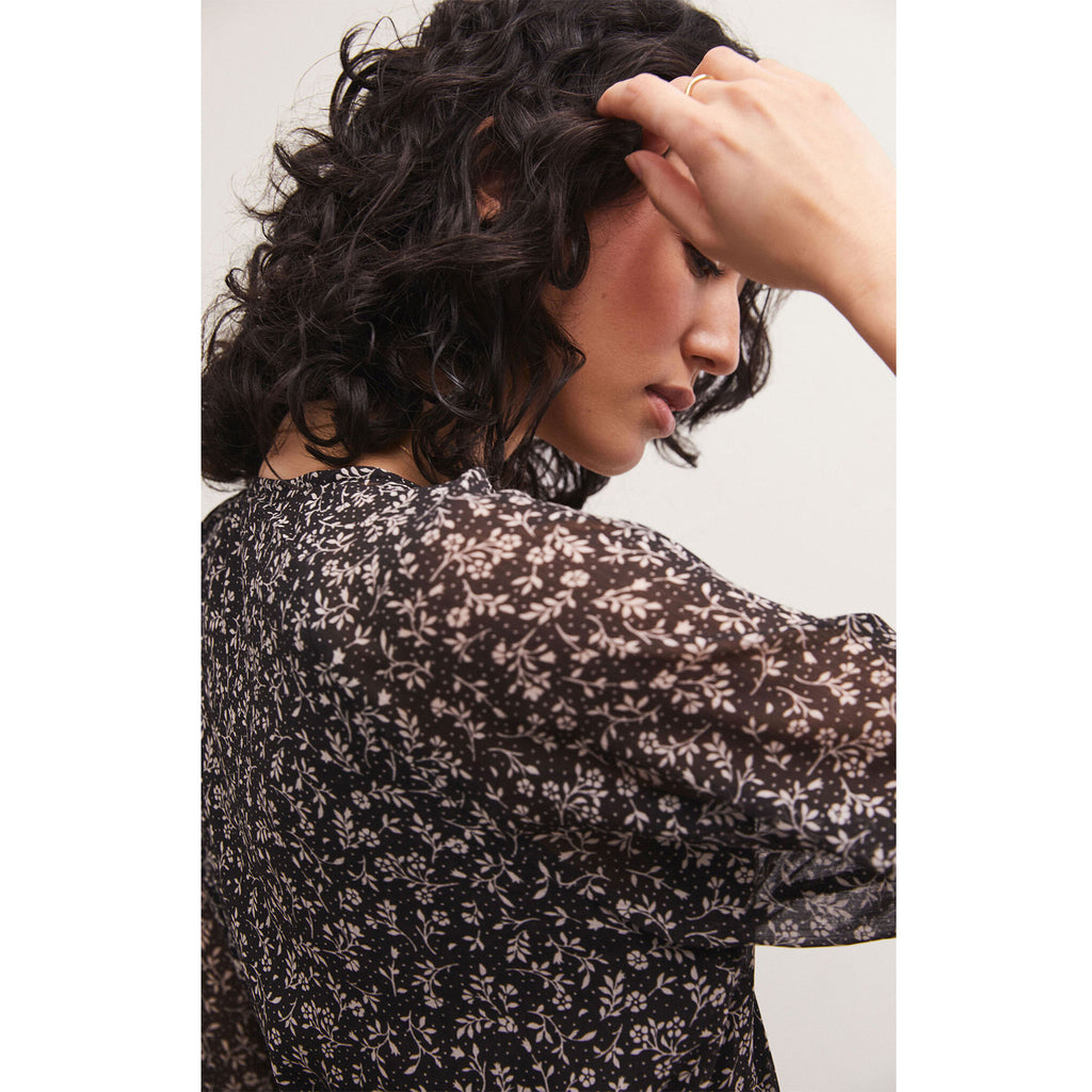 Brunette model wearing Z Supply Della Floral Midi Dress in Black with black boots in front of a white background