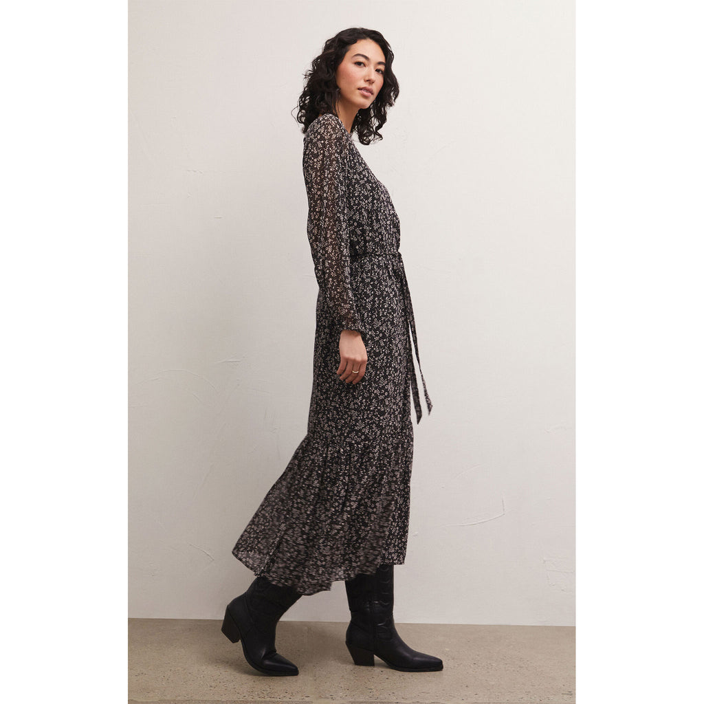 Brunette model wearing Z Supply Della Floral Midi Dress in Black with black boots in front of a white background