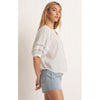Model wearing cut of jean shorts and Z Supply Elliot Lace Inset Top in White