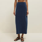 Person wearing a long navy skirt on a plain background