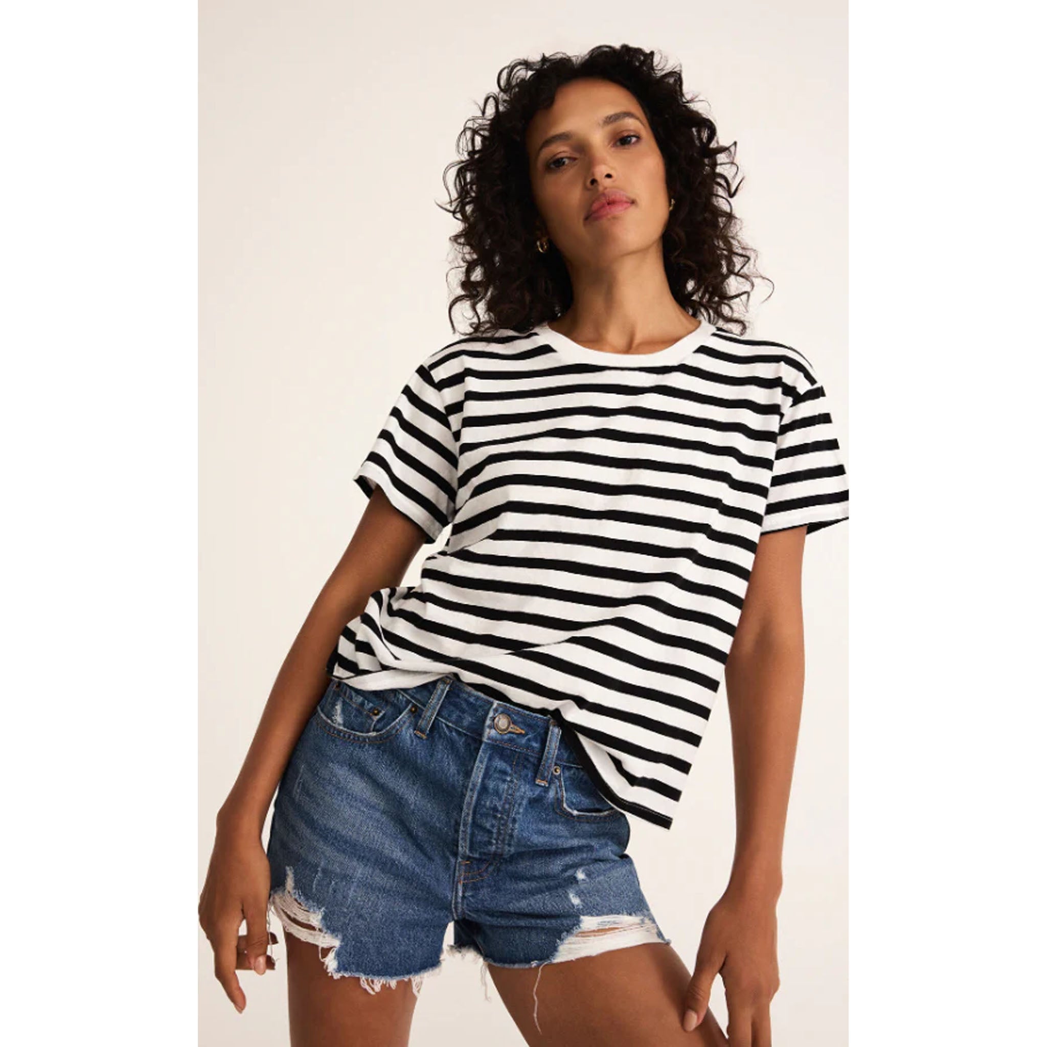 Model wearing jean shorts with Z Supply Go To Stripe Tee in Black  in front of a neutral backdrop 