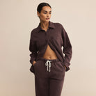 Woman wearing Z Supply Hunter Knit Denim Pant in Chocolate Cherry with matching top against a neutral background