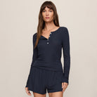 Woman wearing a navy blue long-sleeve top and shorts set on a beige background
