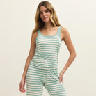 Woman wearing a green and white striped tank top and pants on a beige background