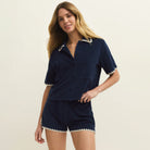 Woman wearing a navy blue outfit with white trim on a beige background