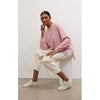 Model wearing white pants and Z Supply Modern Weekender in Smoked Rose sitting on a white stool