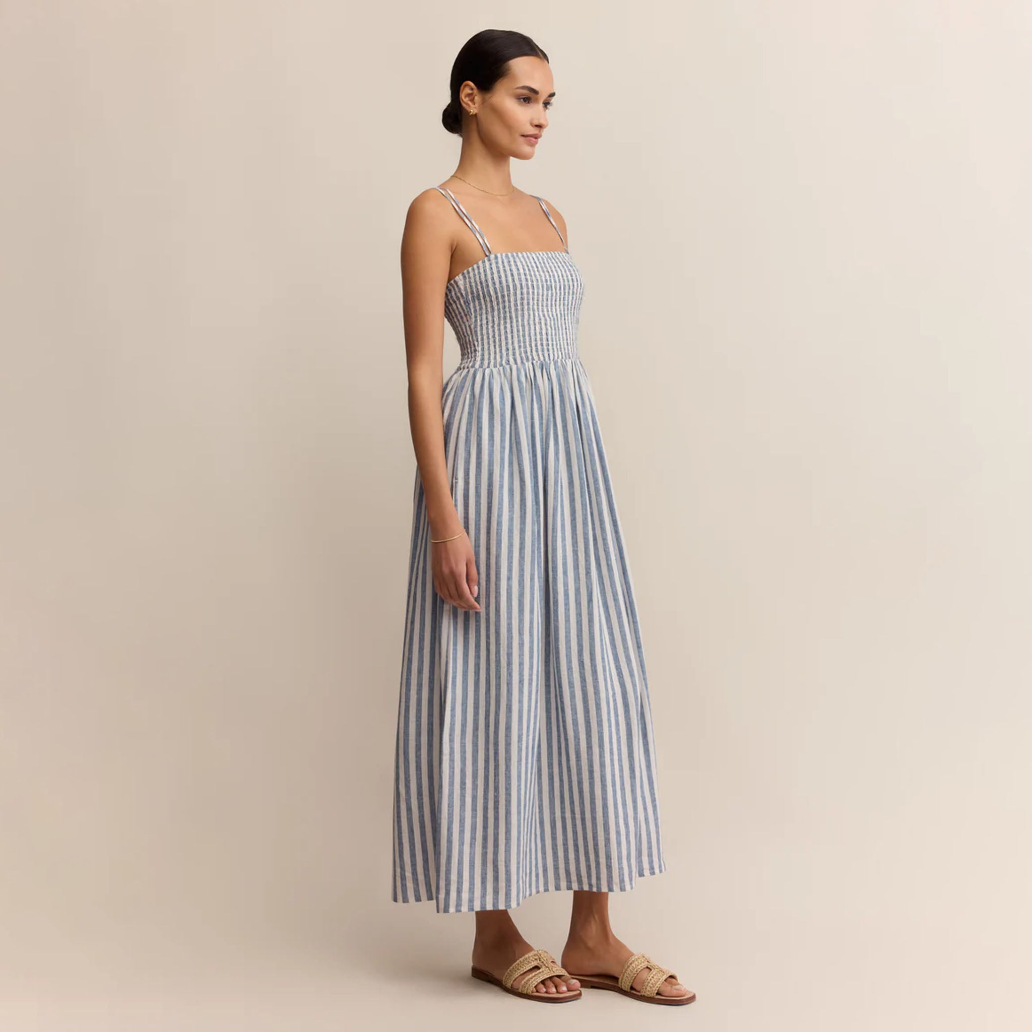 Woman wearing a blue and white striped dress against a beige background