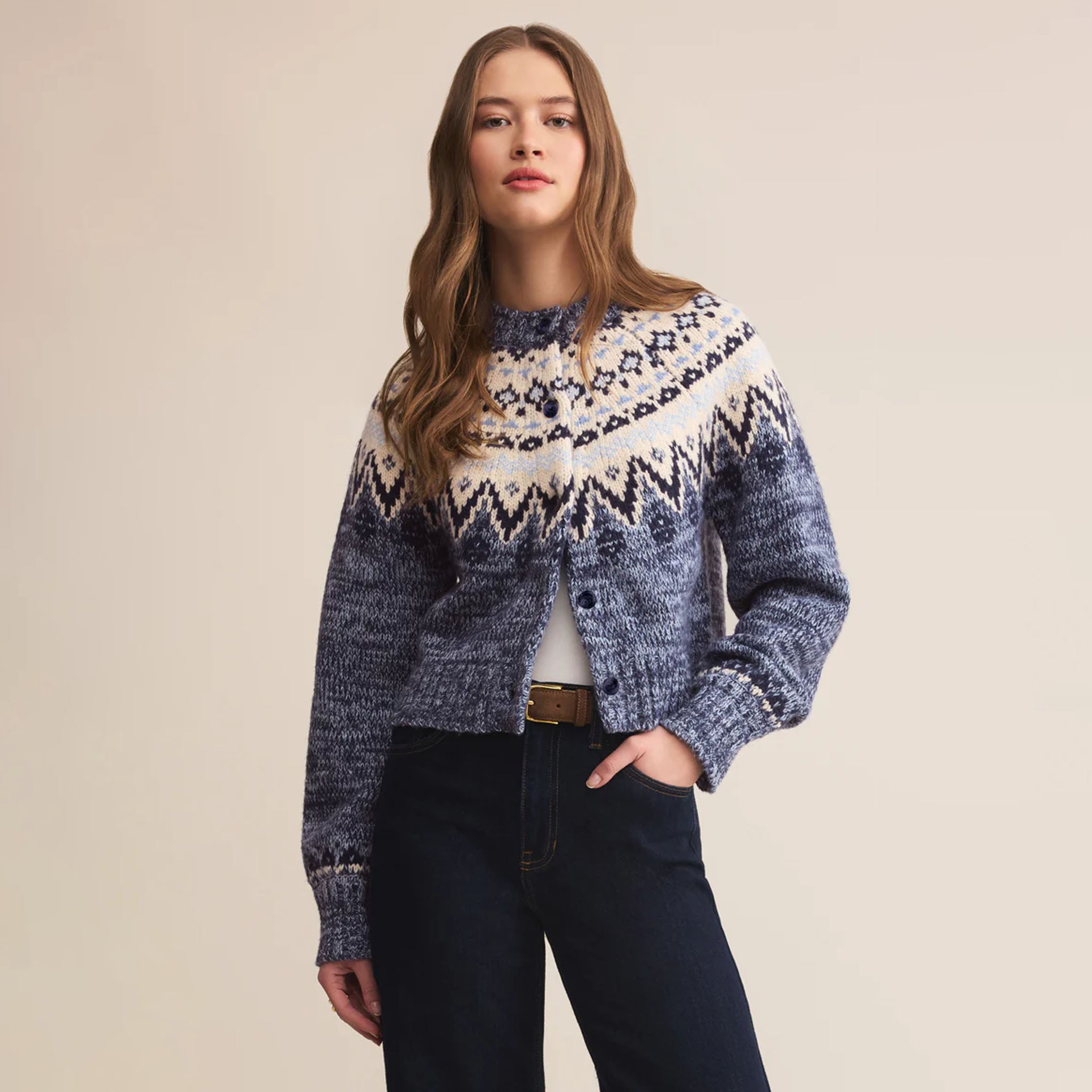 Woman wearing a patterned sweater and jeans on a beige background