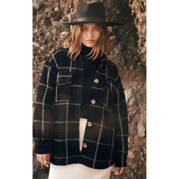 Z Supply Plaid Tucker Jacket in Washed Black on a model wearing a black felt hat in front of a rock pile