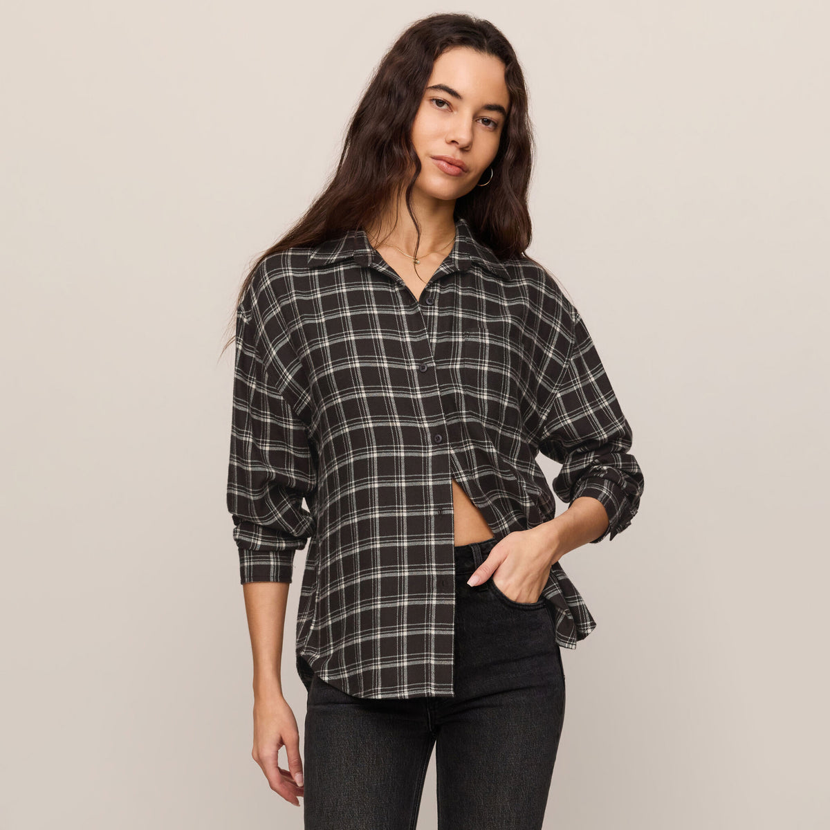 Woman wearing a black and white plaid shirt against a plain background