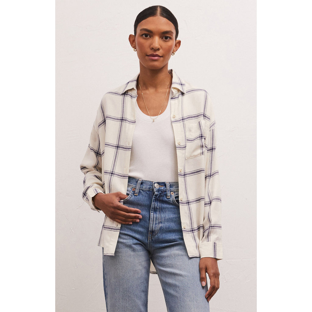 Model wearing jeans and Z Supply River Plaid Button Up in Inca in front of a white wall