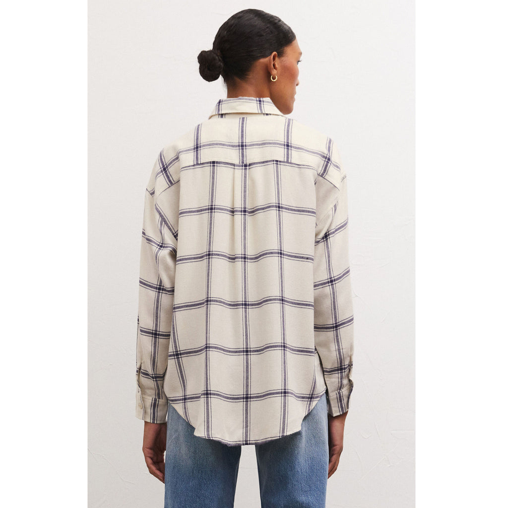 Model wearing jeans and Z Supply River Plaid Button Up in Inca in front of a white wall