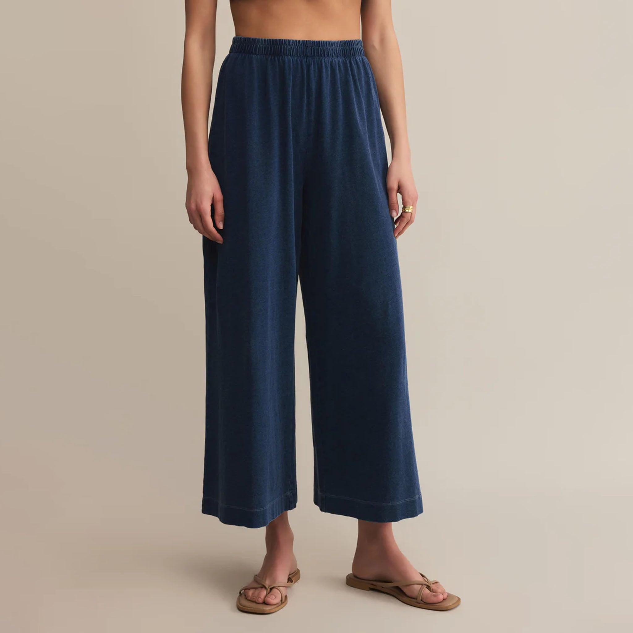 Person wearing blue wide-leg pants on a beige background