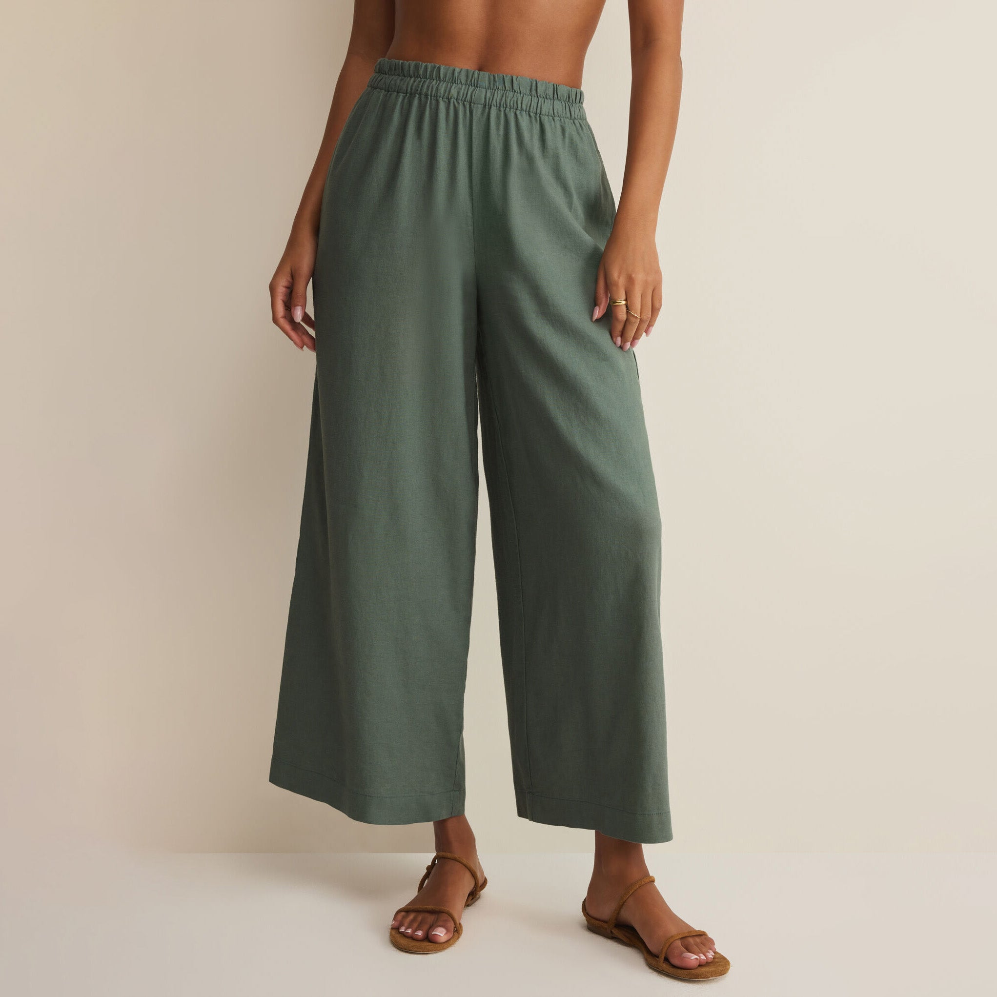 Woman wearing Z Supply Scout Linen Pants in Everglade on plain background at Addison West.