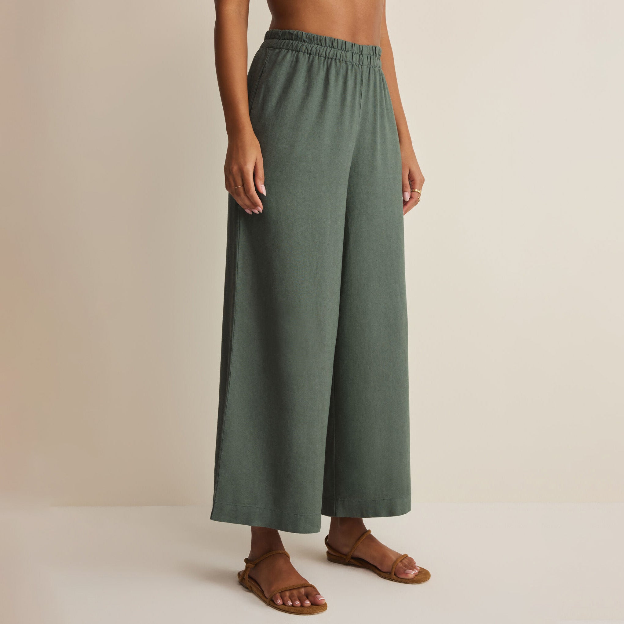 Woman wearing Z Supply Scout Linen Pants in Everglade on plain background at Addison West.