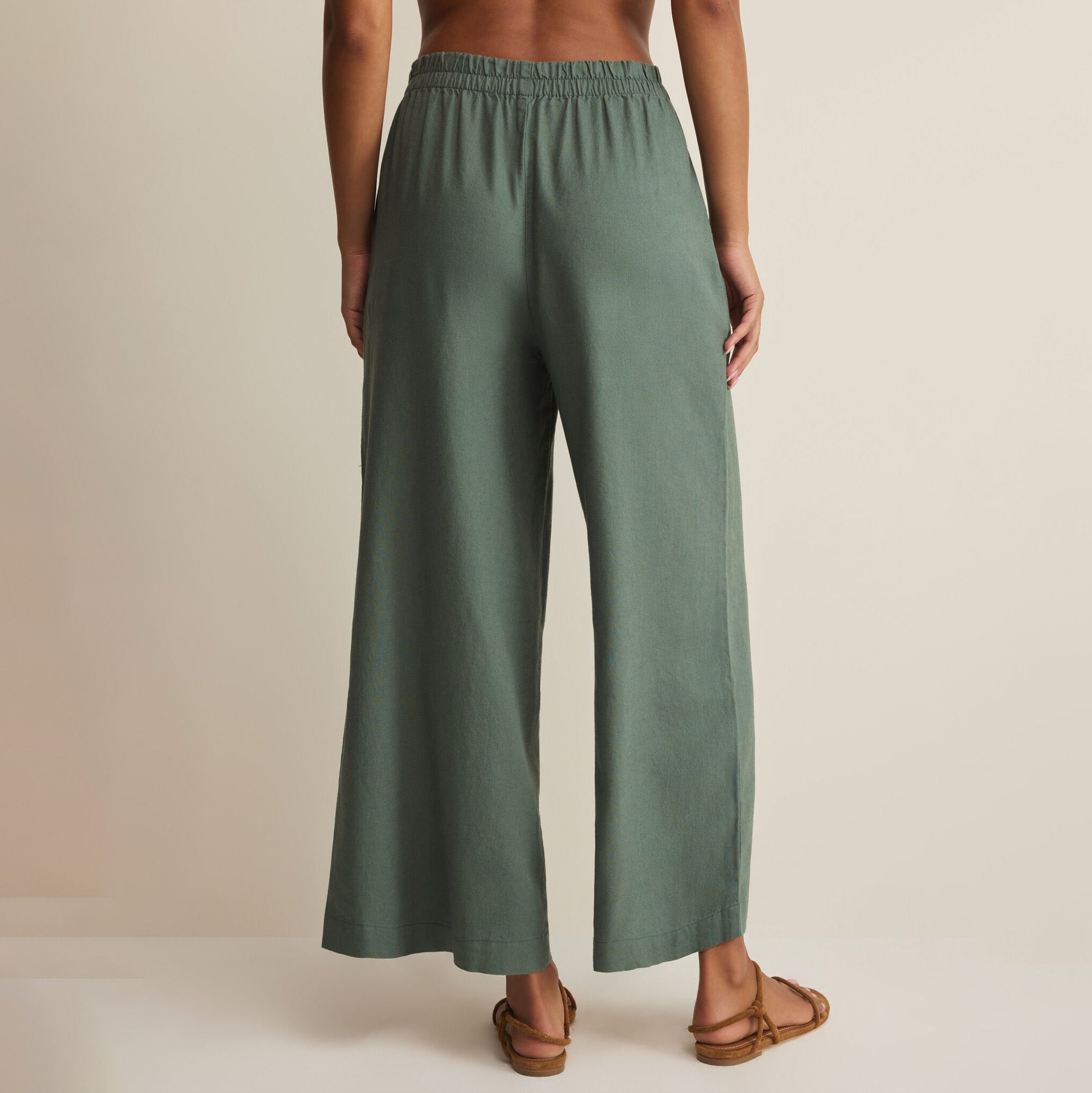 Woman wearing Z Supply Scout Linen Pants in Everglade on plain background at Addison West.