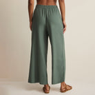 Woman wearing Z Supply Scout Linen Pants in Everglade on plain background at Addison West.