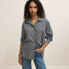 Woman wearing a black and white checkered shirt with rolled-up sleeves against a beige background