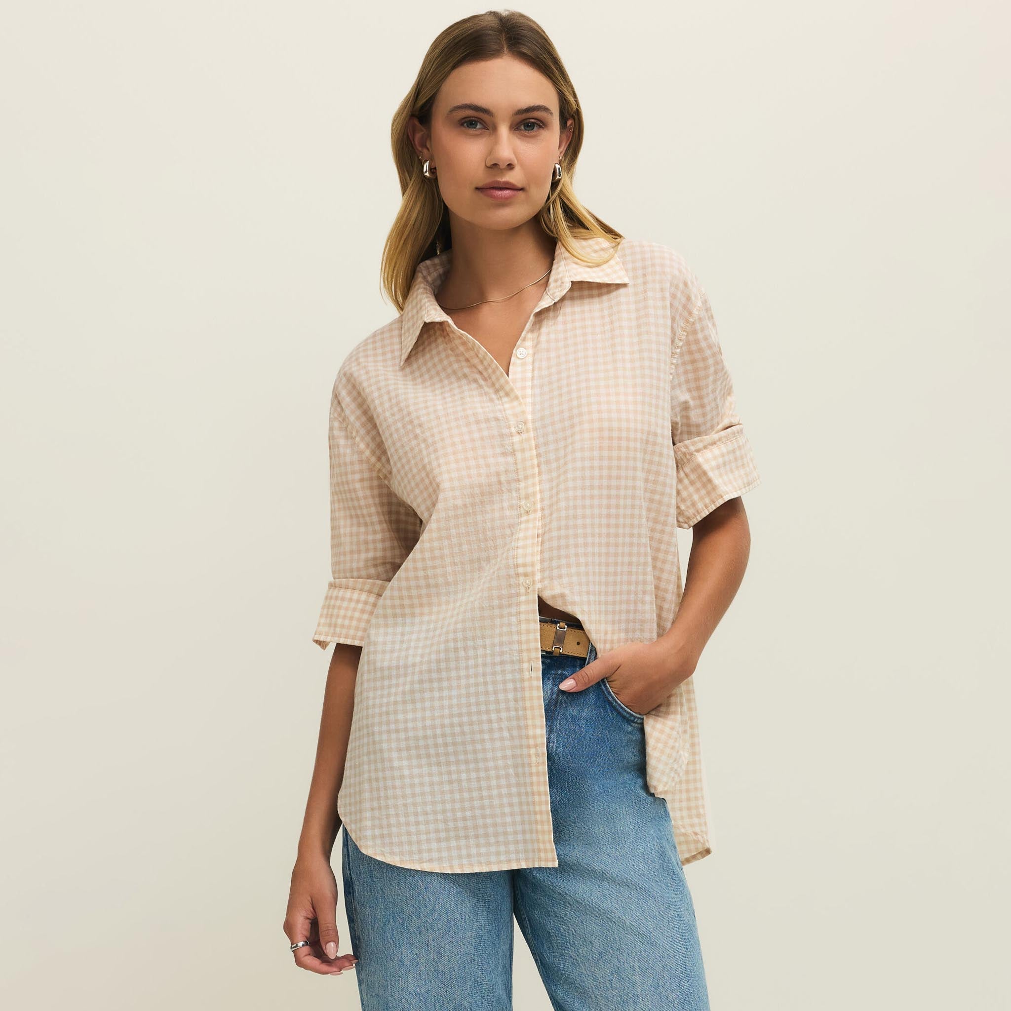 Woman wearing a checkered shirt and jeans on a plain background