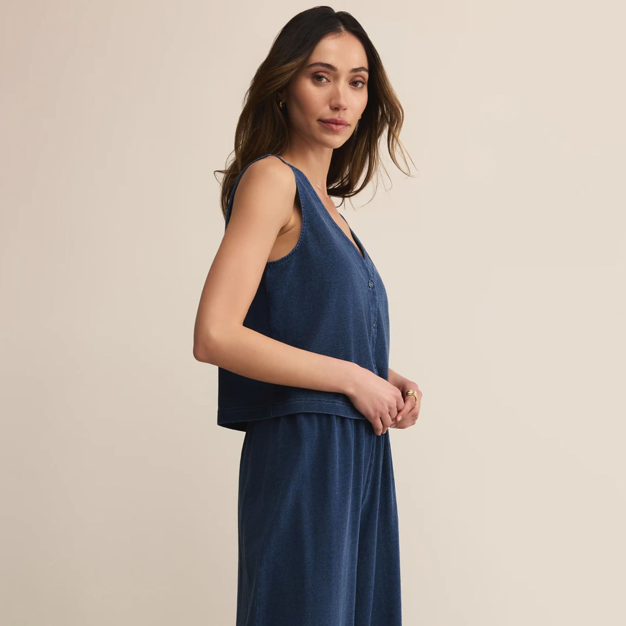 Woman wearing Z Supply Solace Jersey Denim Top Indigo against a beige background