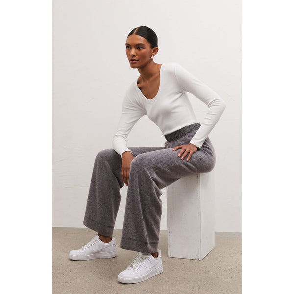 Model sitting wearing white long sleeve tee with Z Supply Tessa Cozy Pant In Charcoal Heather in front of a white wall