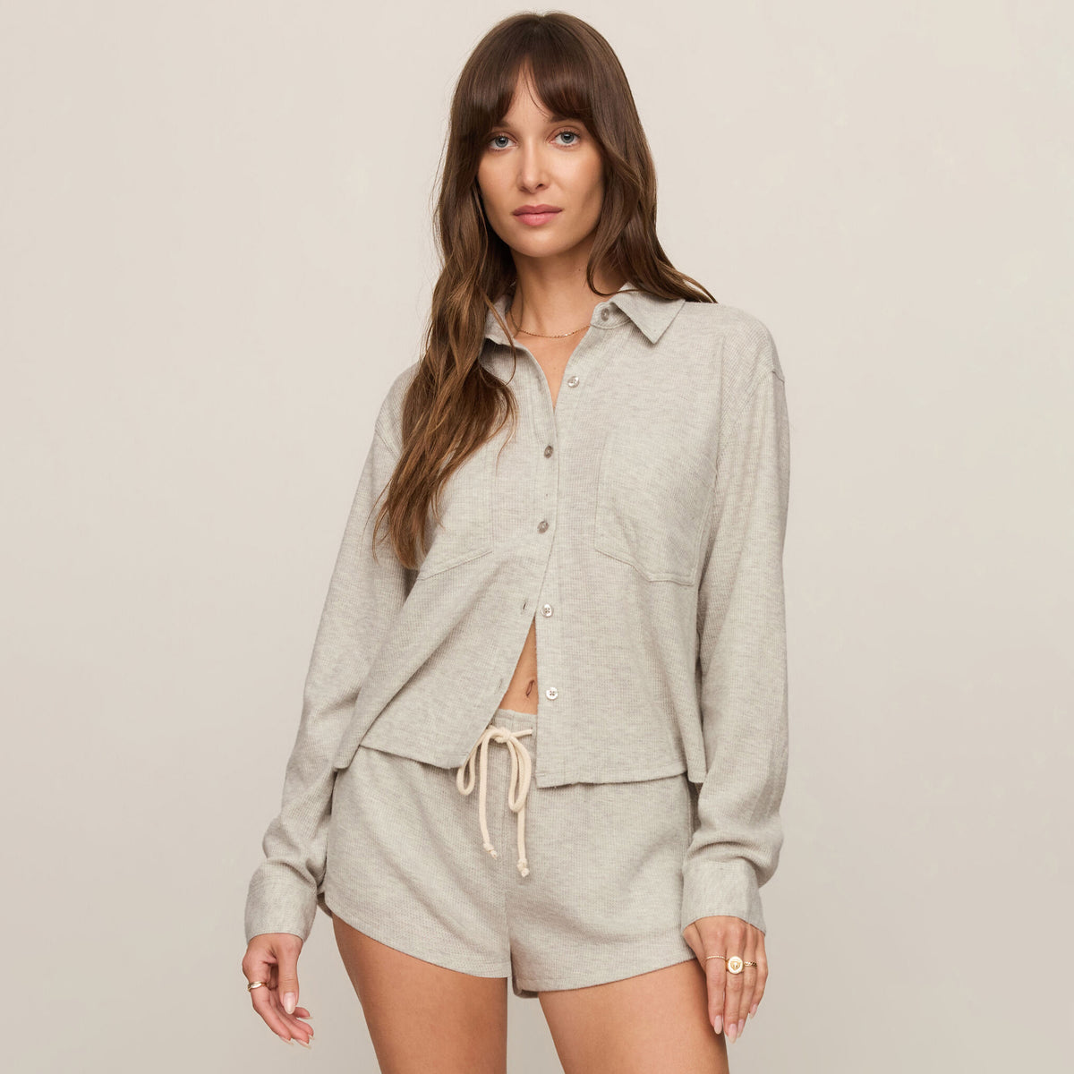 Woman wearing a gray outfit with a matching jacket and shorts on a plain background