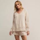 Woman wearing a beige sweatshirt and shorts set on a plain background