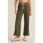 Model wearing Z Supply Huntington French Terry Pant in Grape Leaf in front of a beige background