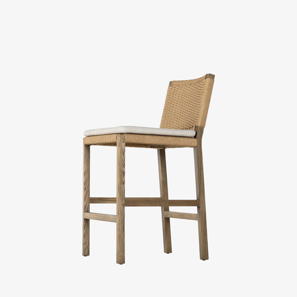 Four Hands Zuma bar stool with beige cushion and woven back in Dune Ash on a white background