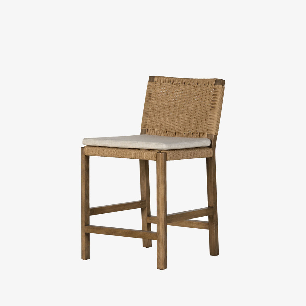 Four Hands Zuma counter stool with beige cushion and woven back in Dune Ash on a white background