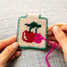 Cherries Needlepoint Keychain Kit held by a model at Addison West