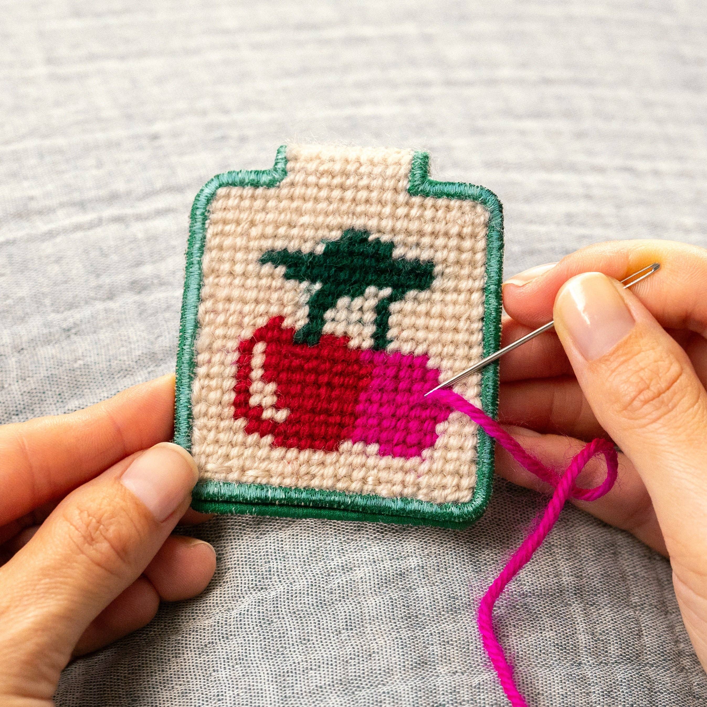 Cherries Needlepoint Keychain Kit held by a model at Addison West