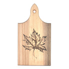 A rectangular wooden cutting board with a pointed top and a hanging hole, featuring a dark engraved maple leaf design on a light natural wood grain background.