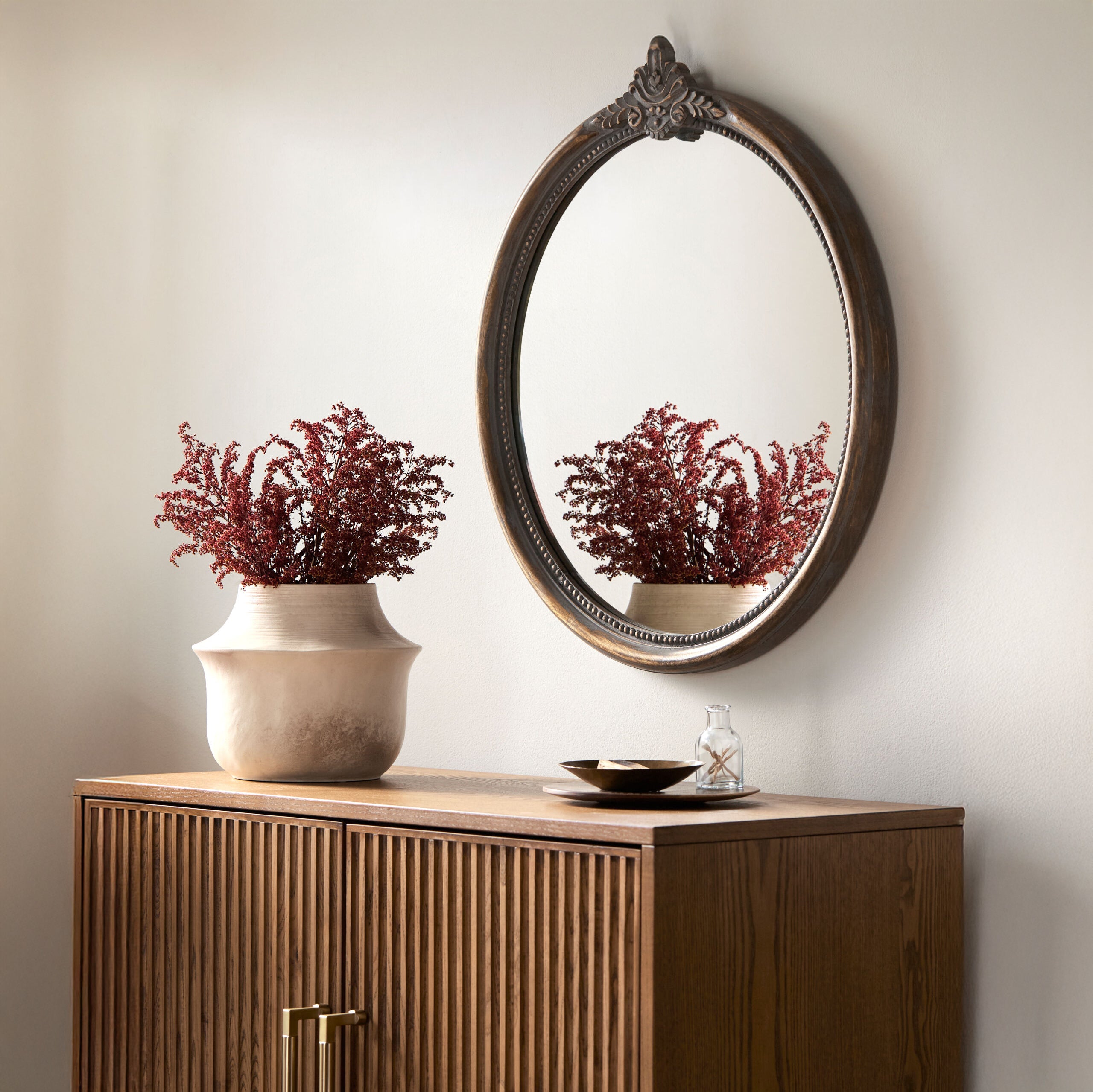 Aden Accent Mirror on a beige wall above a table at Addison West