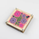Wooden flower press with pink and purple floral illustrations on a white background