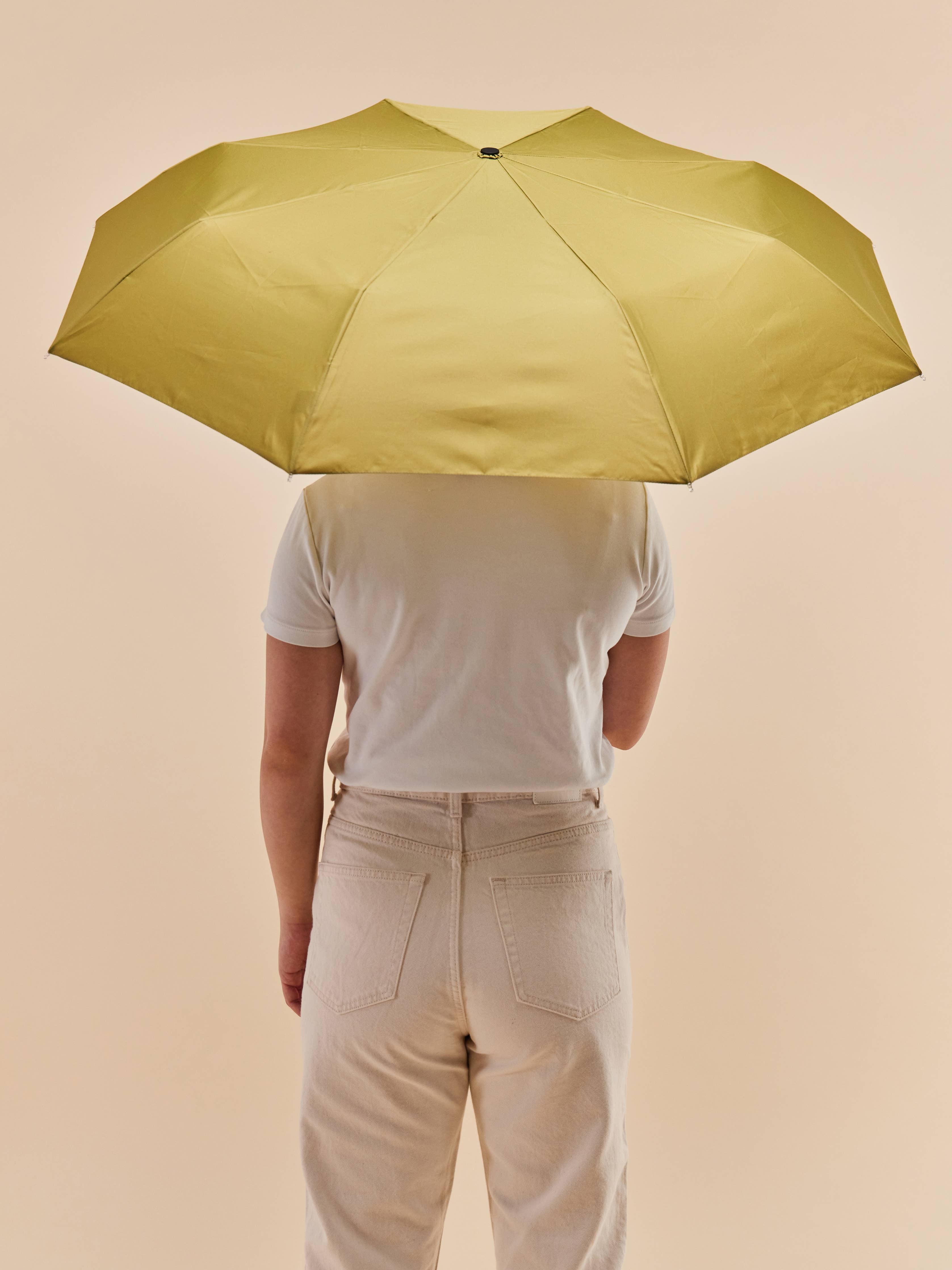 Person holding Original Duckhead Olive Eco-Friendly Umbrella on a white background at Addison West
