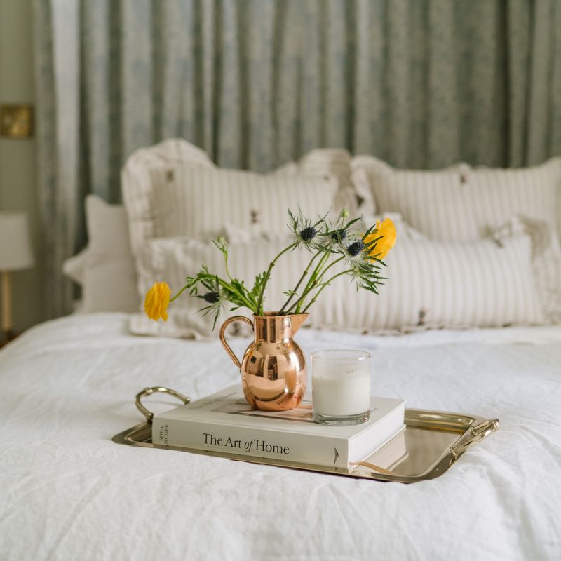Heirloom Copper Syrup Pourer used as a vase on a tray on a bed with flowers in it at Addison West