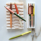 Colorful pens on a marble surface with packaging in the background