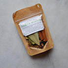 Packaged simmer pot spice with visible ingredients on a gray background