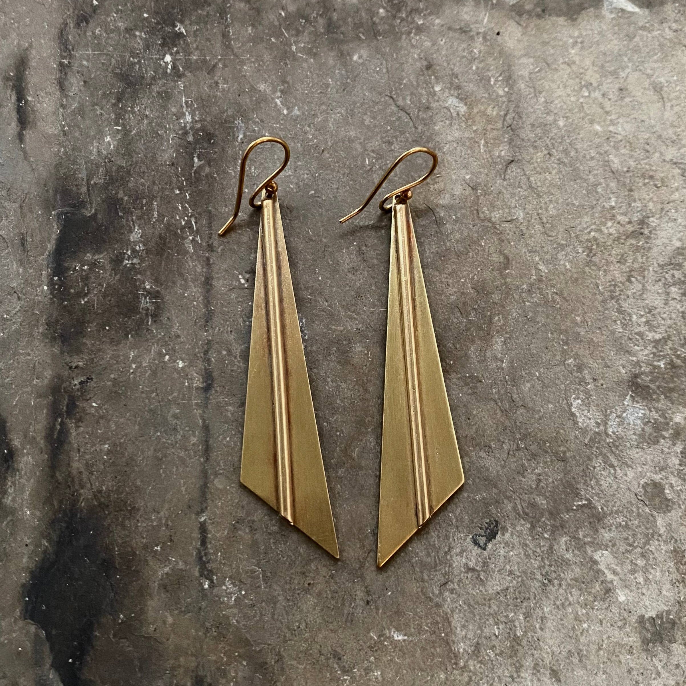 Tiny Anvil Brass Slope Earring on a grey background at Addison West