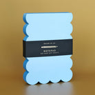 Blue scalloped notepad with a black label on a brown background