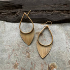 Tiny Anvil Brass Flora Earrings on a grey background at Addison West