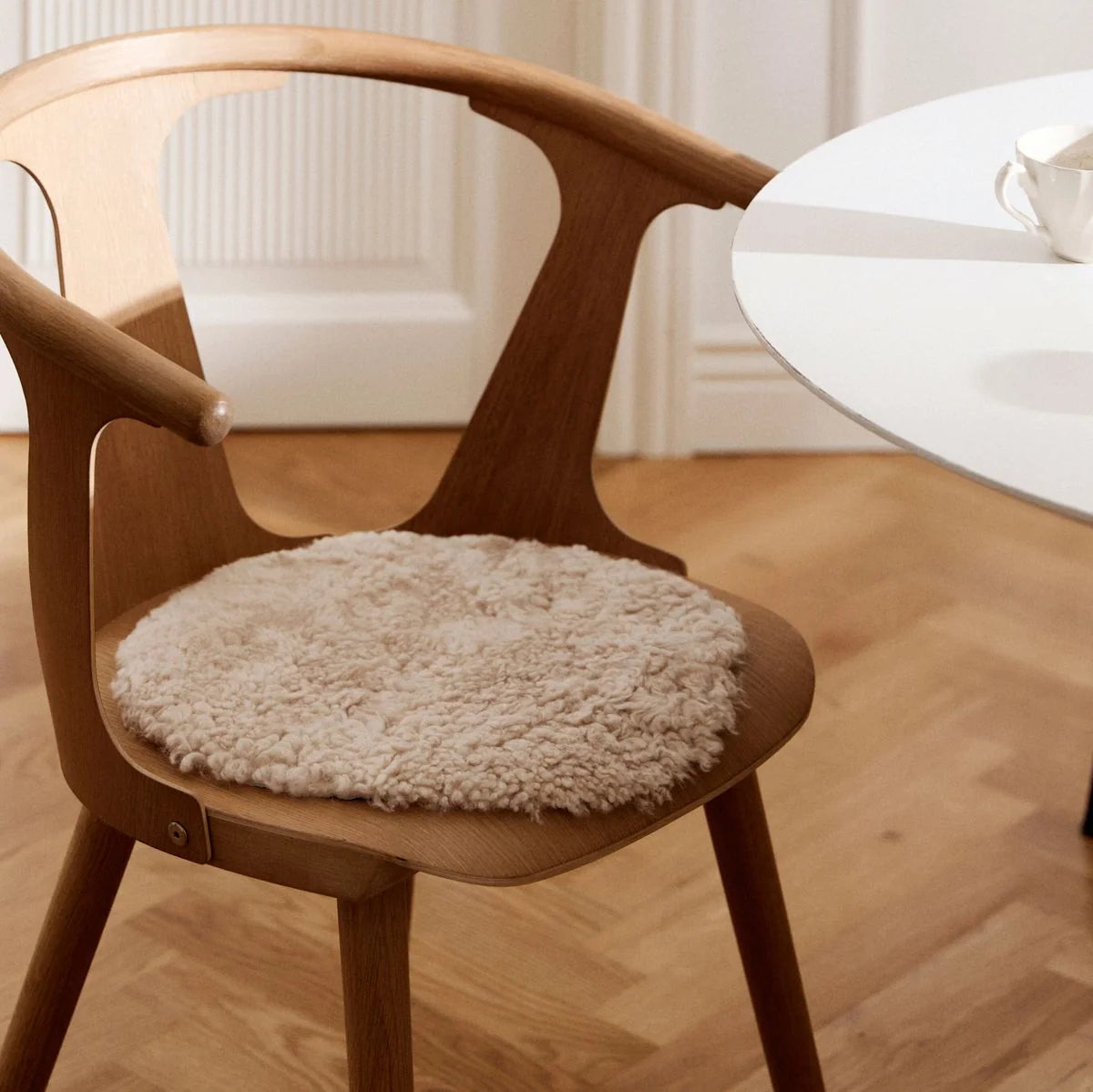 Short Wool Curly Sheepskin Seat Cover in Pearl on a dining chair at Addison West