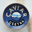 Caviar Osetra logo on a blue and gold plate with a marble background
