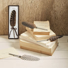 Feather pens on books with a natural wood background at Addison West