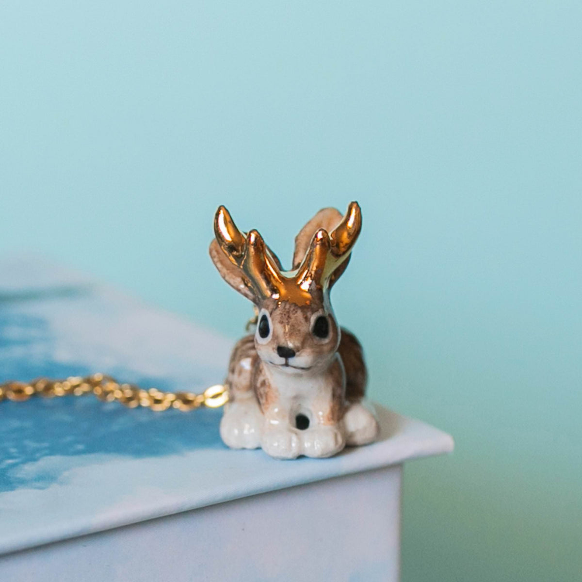 Camp Hollow Jackalope Necklace on a blue background at Addison West
