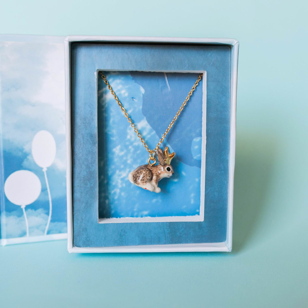 Camp Hollow Jackalope Necklace on a blue background at Addison West